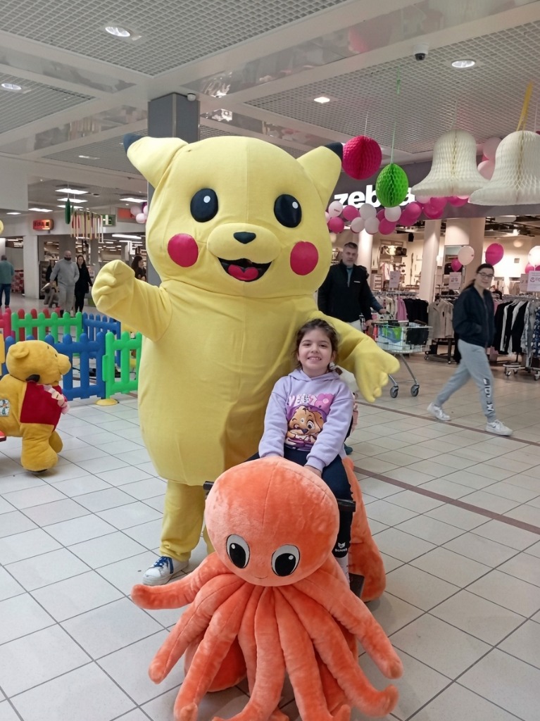 Mascotte Pikachu géante et fillette sur peluche pieuvre orange